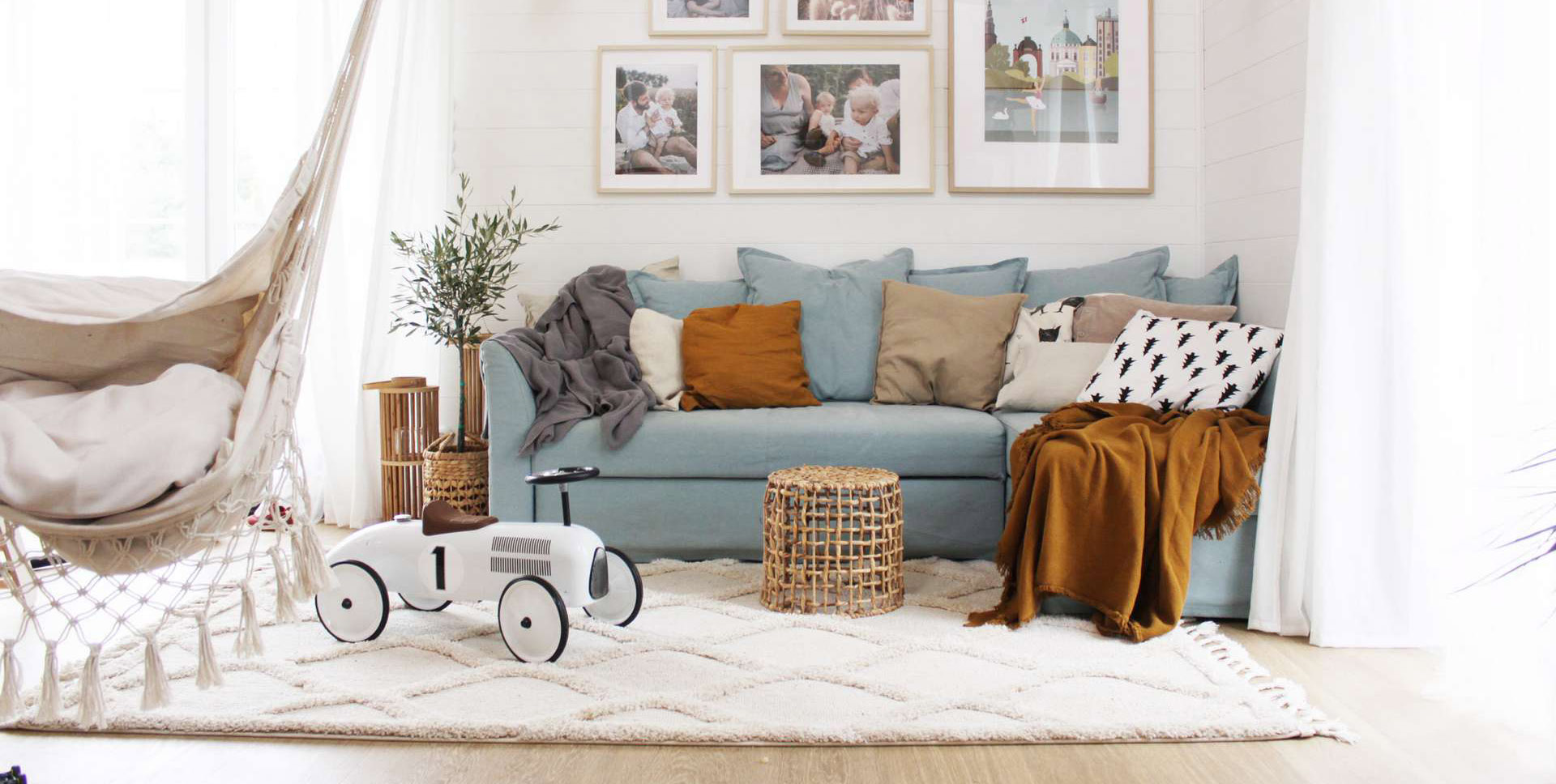 huśtawka boho, oliwka w salonie, biała boazeria na ścianie, białe deski, sofa kanapa Ikea
